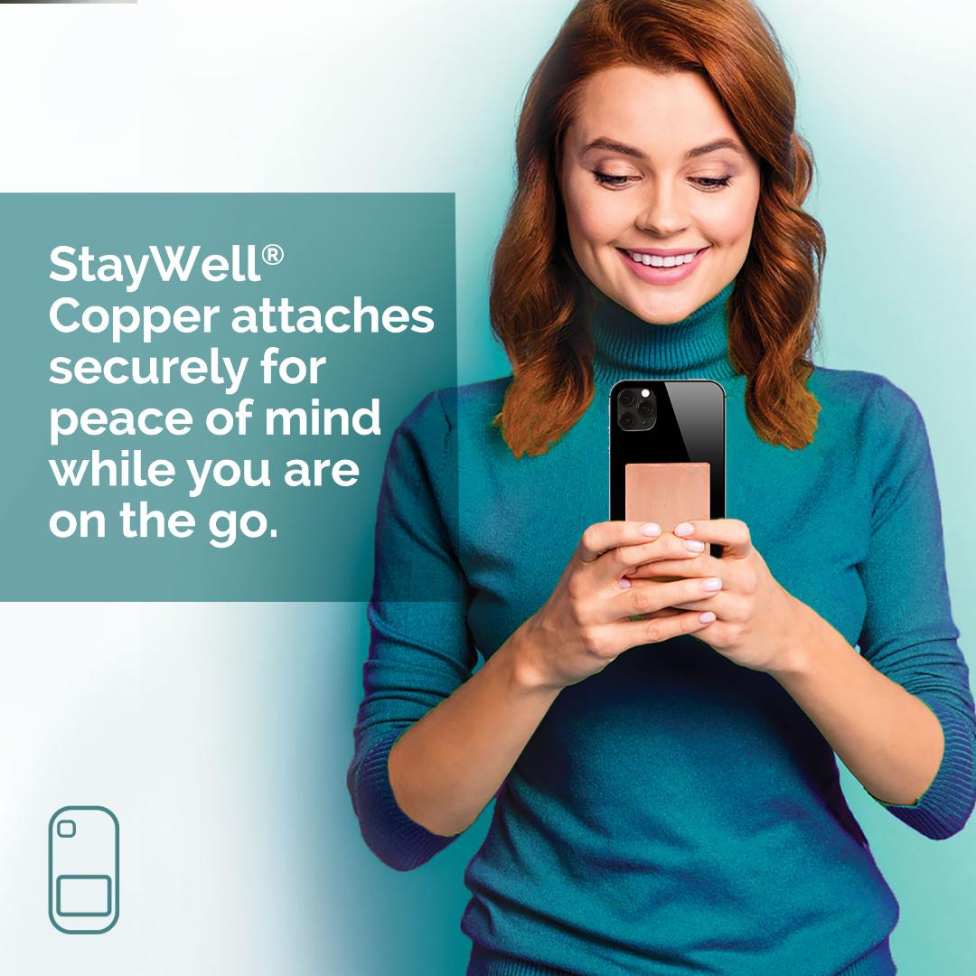 Red haired woman holding phone with StayWell Copper Phone Patch. StayWell Copper attaches securely for peace of mind while you are on the go.