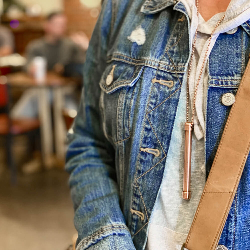 Shows user wearing One 4" Magic Wand Halo Necklace on 30" copper beaded ballchain necklace. Necklace is lacquered so will not turn neck green. Made in USA from natural antimicrobial copper. Roll between hands to kill 99.97% of bacteria, virus, and germs. All Natural Hand Sanitizers, Chemical Free, Lasts Forever. Will not chap hands or make sore. Recyclable. EPA registered. Patented