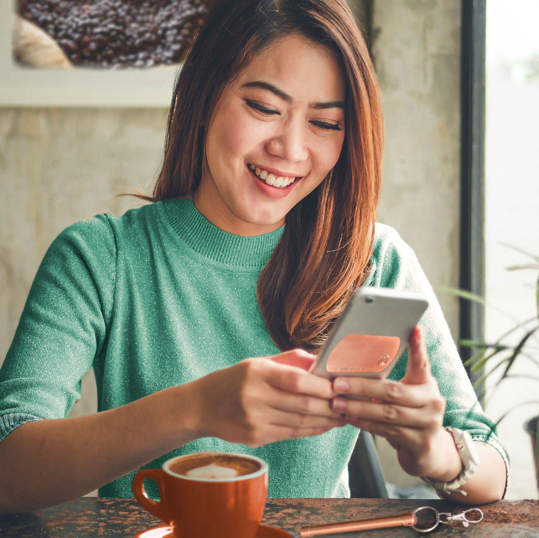 woman drinking coffee and using her phone with StayWell Copper Patch on the back of it